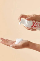 Person holding a bottle of 'Want Body' volume foam with a beige background - Hair Care Canada