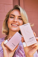 Woman holding Kevin Murphy hair products against a pink brick wall - Hair Care Canada