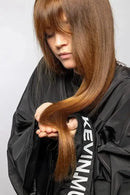 Person holding long brown hair with a black jacket featuring 'Kevin Murphy' branding - Hair Care Canada